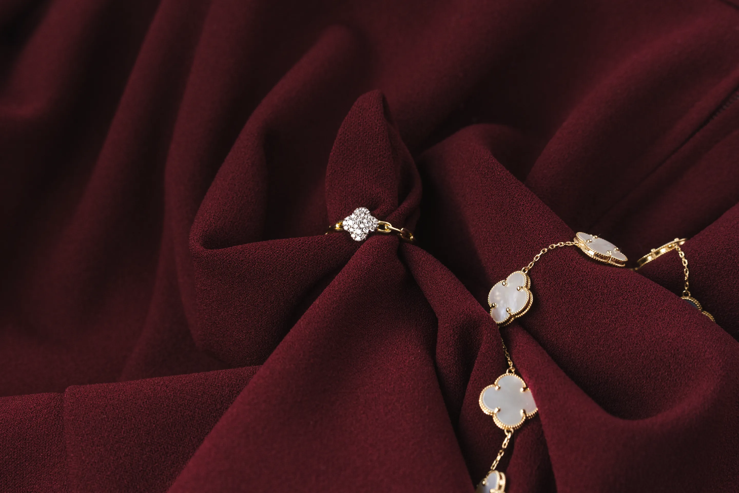 A clover ring and bracelet from the NovaOro collection on burgundy fabric